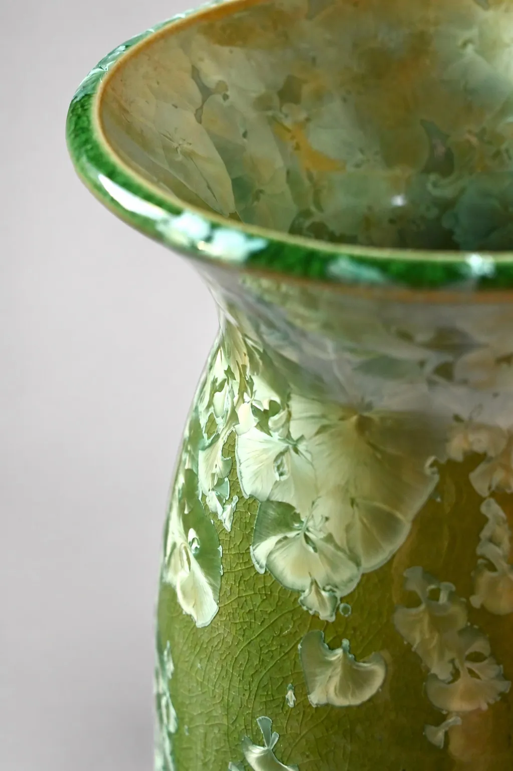 Close view of the flared rim and neck, cream crystal blooms clustering over green with a finely crazed surface