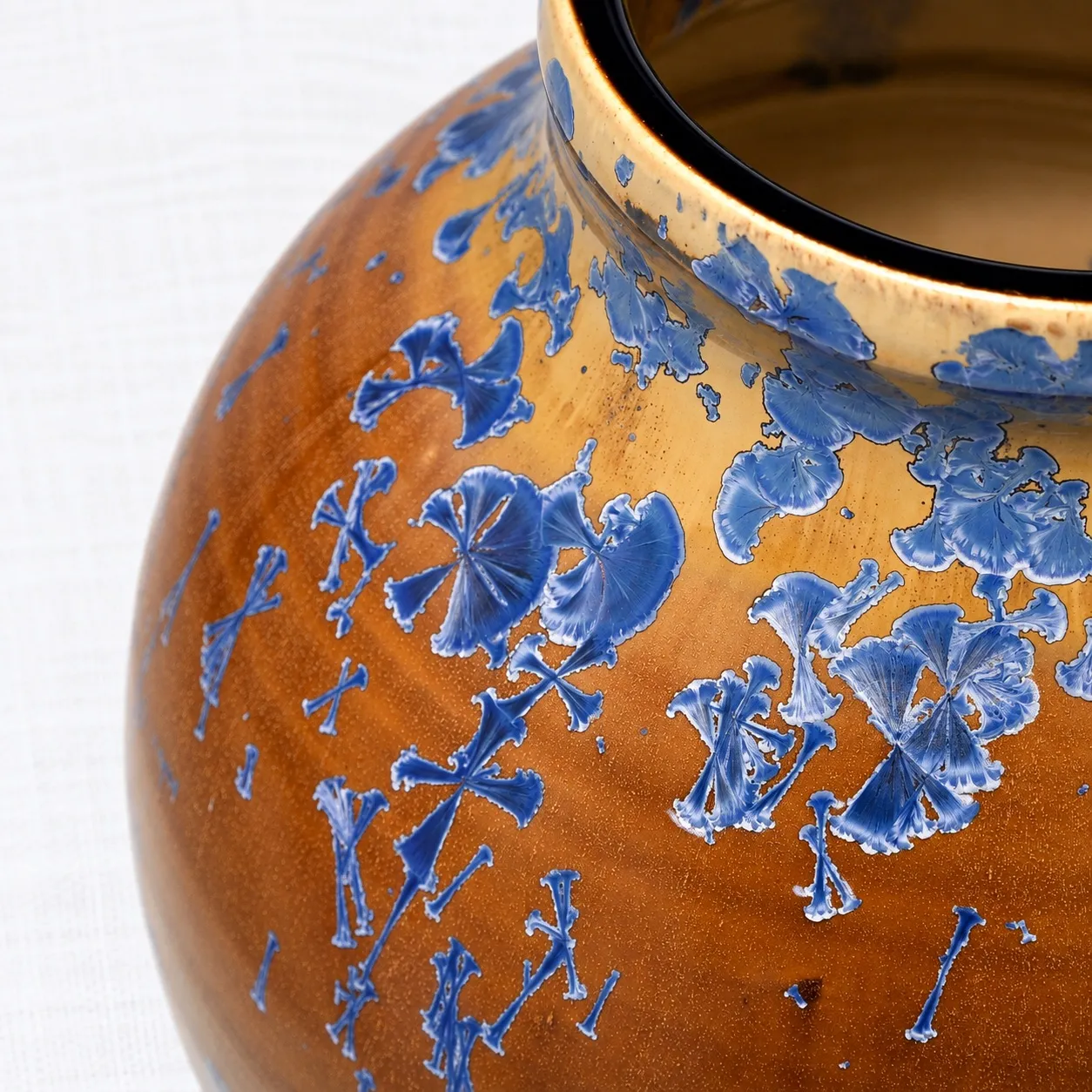 Close view of the glaze, cobalt crystals opening into little fans and stick shapes across amber