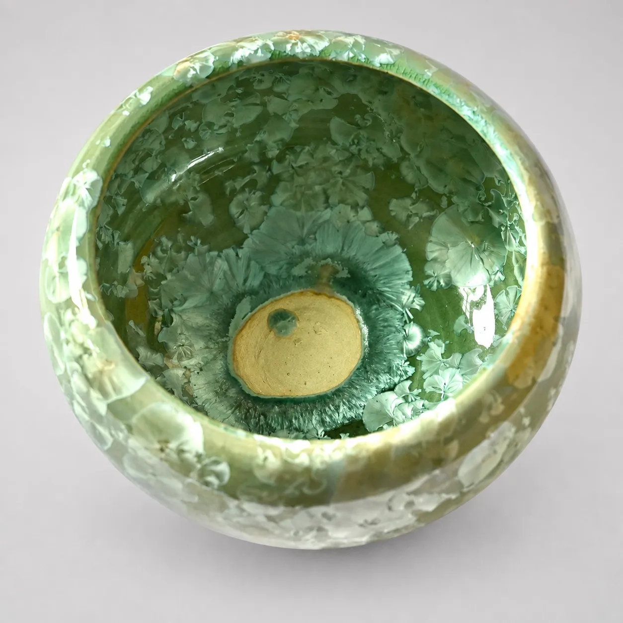 Looking down into the bowl, a green crystalline interior with a pool of amber at the centre like an island in the green