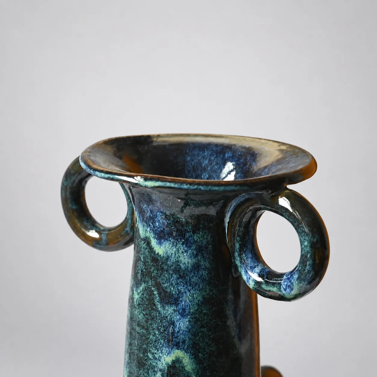 Close view of the neck and flared rim with two ring handles, deep blue and turquoise mottling over the glaze