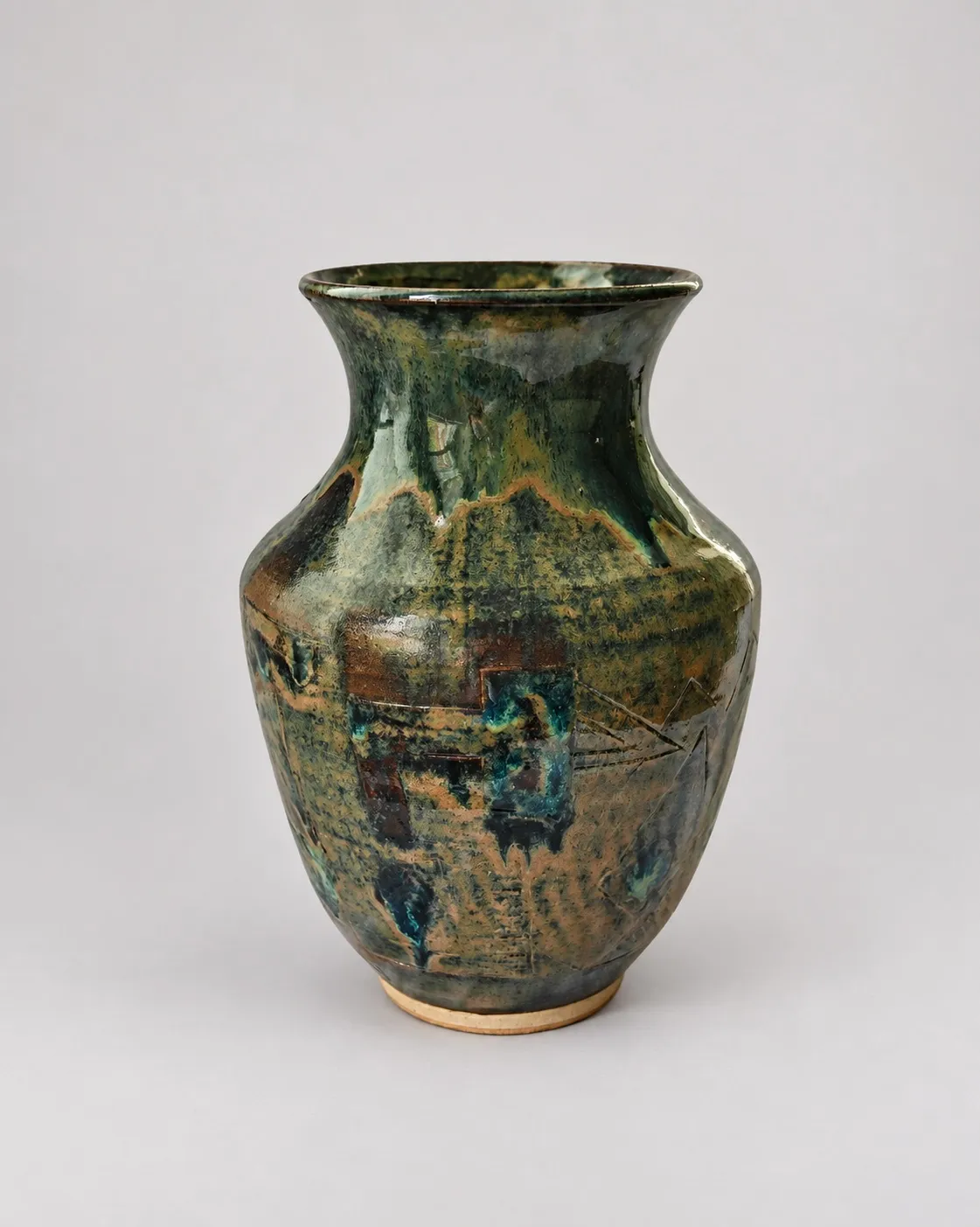 A baluster vase in mottled green and ochre, the lower body incised with fine geometric lines (arrows, rectangles and circles) with turquoise gathering where the glaze pools in the cuts