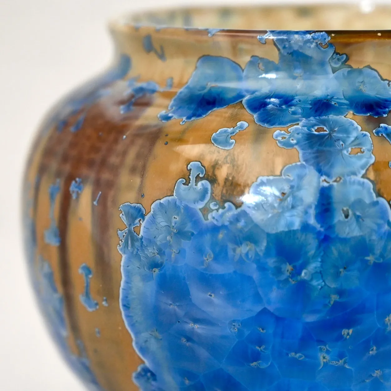 Close view of the exterior, large blue crystal blooms spreading over an amber ground