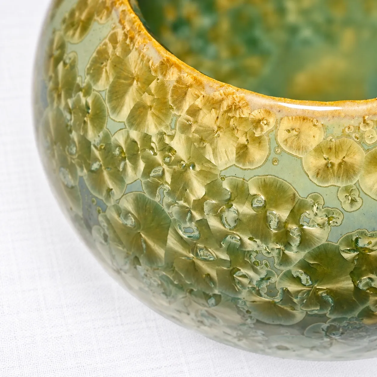 Close view of the rim, where amber and green crystals cluster like lichen along the lip
