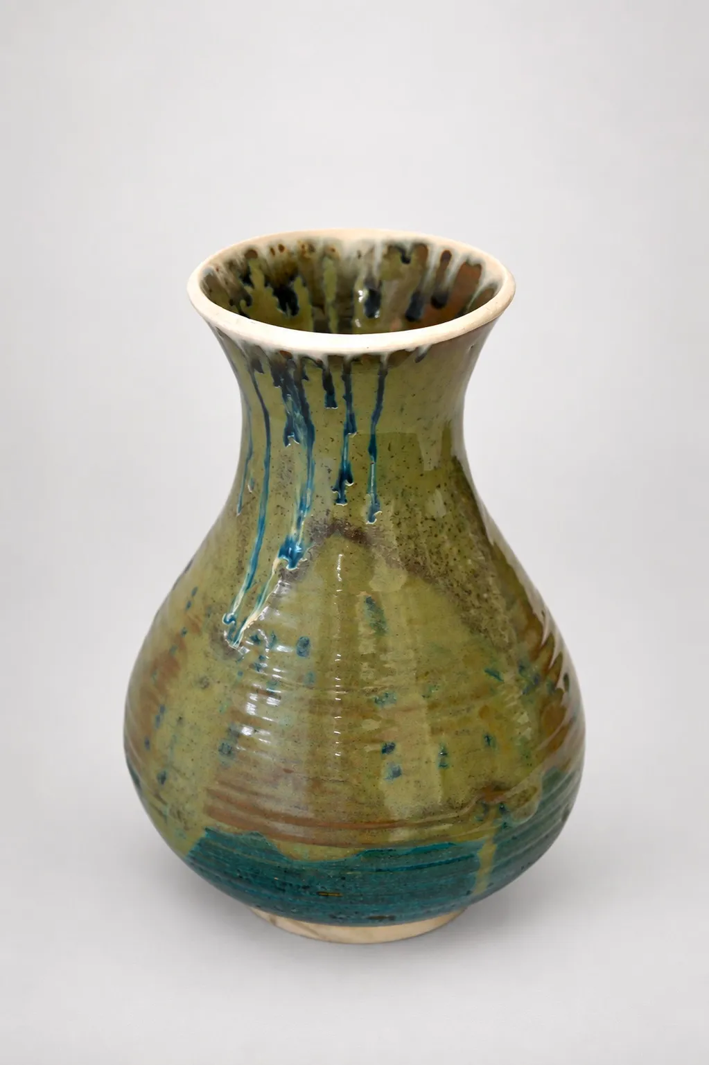 A pear-shaped vase with a flared rim, olive-green glaze with blue rutile streaks running down from the rim