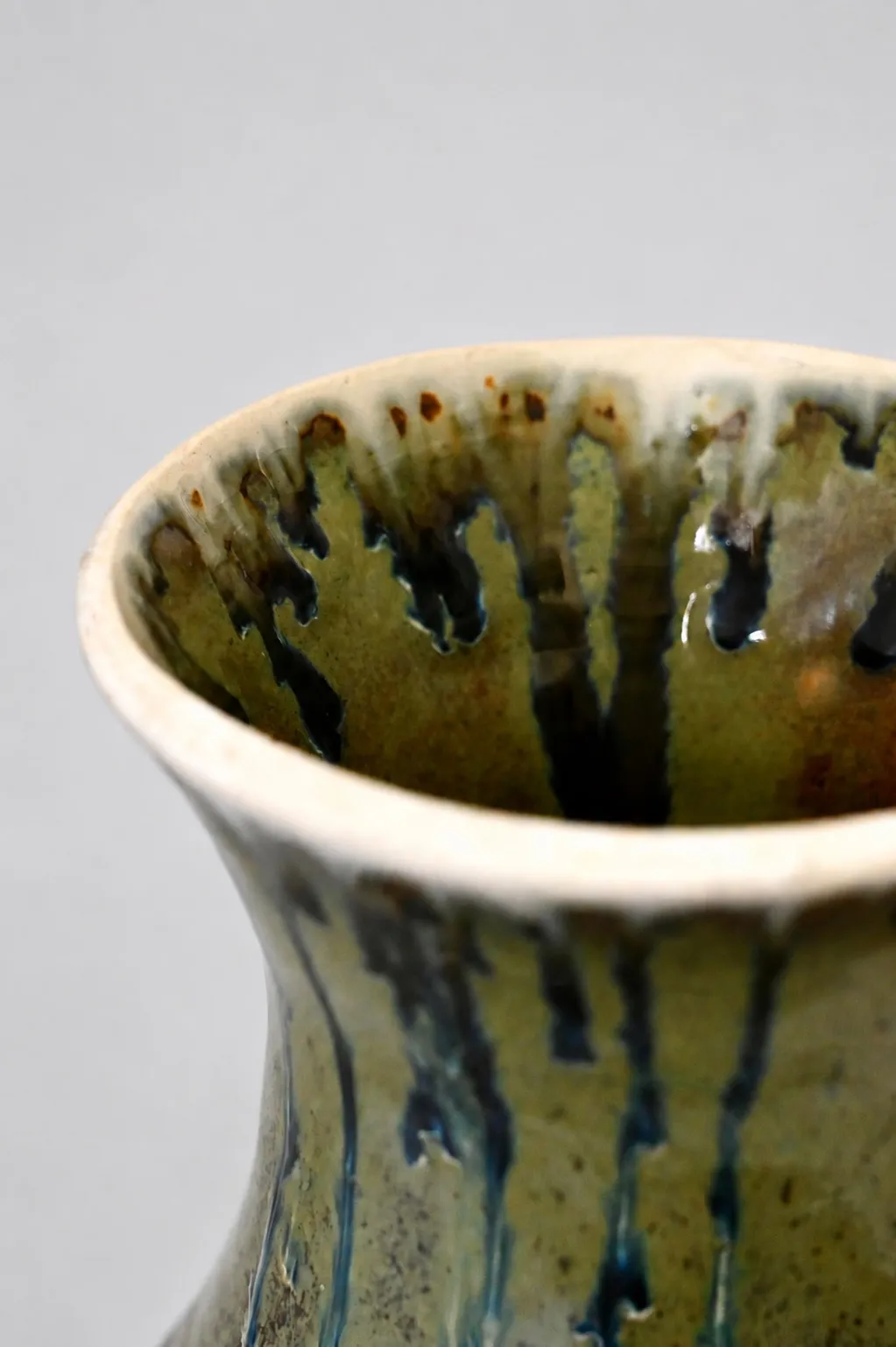 Close view of the rim, dark ash runs falling from a cream lip into the olive-green interior